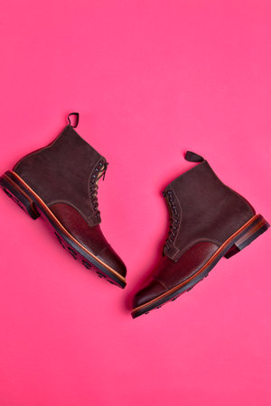 Flatlay View of Dark Brown Grain Brogue Derby Boots Made of Calf Leather with Rubber Sole Placed Over Pink Burgundy Background. Vertical imageの写真素材