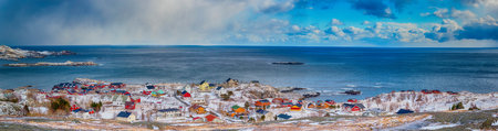 Lofoten Islands Scenery with Group of Houses Against Snowy Mountains on Background. During Spring...