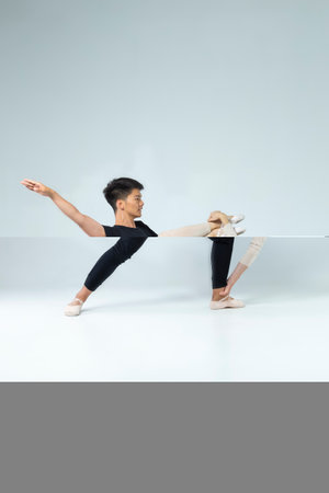 Ballet Dance Ideas. Sportive Couple of Asian Man and Caucasian Woman Performing As Ballet Dancers On Grey in Studio During Suppots As Classical Dance And Choreography.Vertical Compositionの写真素材