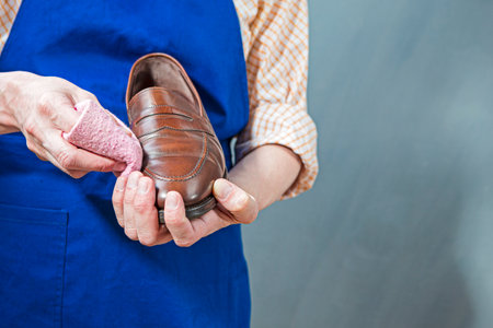 Extreme Closeup of Hands of Professional Shoes Cleaner with Cloth For Brown Leather Penny Loafers Shoes While Cleaning in Workshop. Horizontal Compositionの写真素材