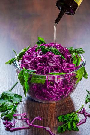 Bowl of Shredded Red Cabbage With Pouring Olive Oil Placed Over Wooden Brown Background as Vegetarian Healthy Food. Vertical Orientationの写真素材