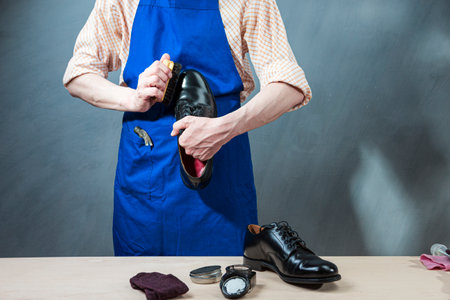 Male Shoes Cleaner with Cloth For Black Leather Polished Derby Shoes Cleaning While Working in Workshop. Horizontal Shotの写真素材