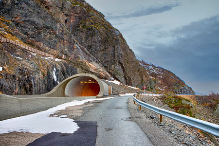View of Asphalt Road Leading to Rocky Mount Tunnel Entrance Carved into Mountainside at Lofoten Islands in Norway.Horizontal Image Compositionの写真素材