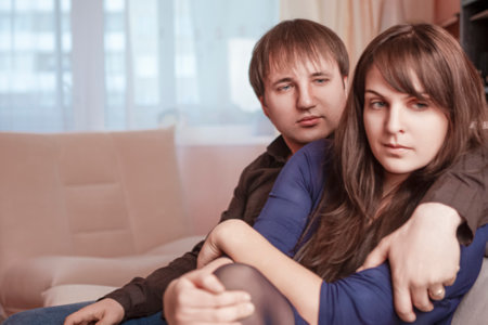Negative Relationships of Young Caucsian Displeased Disgruntled Husband and Wife Sitting in Room Environment Showing Depressed Feelings.Horizontal Shotの写真素材