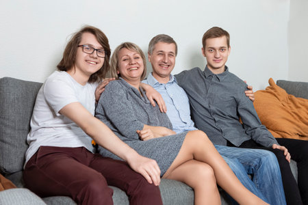 One Happy Caucasian Family Get Together Embracing and Sitting on Sofa Indoors With Positive Expression. Horizontal imageの写真素材