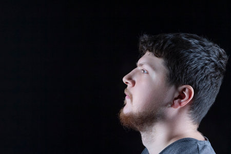 Headshot Portrait of Calm Tranquil Mature Caucasian Brunette Man With Beard With Curious Positive Expression Over Black Background. Horizontal Imageの写真素材