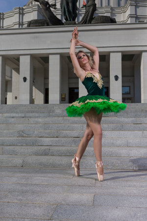 Professional Caucasian Ballet Dancer in Green Tutu Dress Posing With Lifted Hands Outdoors. Vertical Imageの写真素材