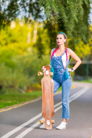 Winsome Beautiful Female Skateboarder Hipster Girl With Longboard Posing on Road While Standing.Vertical Imageの写真素材