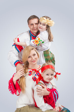 Relationships Concepts. Young Happy Family Together Embraced With Two Little Girl in Traditional National Costumes. Vertical Orientationの写真素材