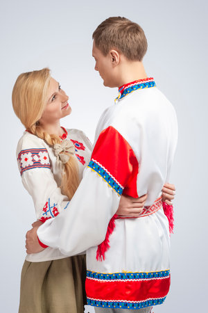 Loving Embraced Caucasian People in National Belarussian and Russian Decorated Embroidery Costumes Against White. Vertical Orientationの写真素材