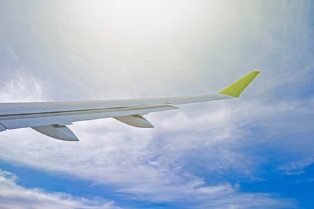 Aerial View Aircraft Wing During Flight Against Open Blue Sky With Light Clouds and Sunshine. Horizontal Imageの写真素材