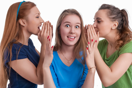 Company of Three Expressive Young Funny Caucasian Girlfriends Sharing Their Secrets Whispering to...