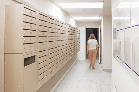 Blurred Image of Woman Walking in Corridor Along With Line of Mailboxes in the Newly Built Apartment Building. Horizontal imageの写真素材