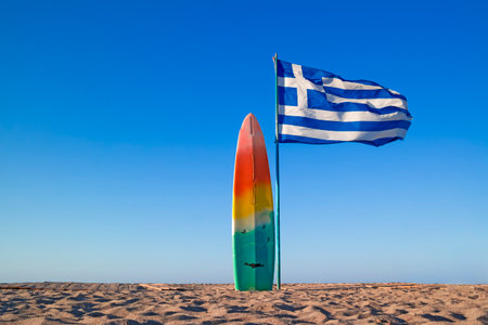 Windsurfing Board Near Flag of Greece on Sandy Empty Lonely Picturesque Beach on Crete Island in Greece. Horizontal Imageの写真素材