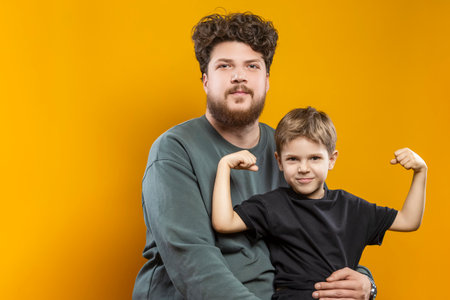 Young Smiling Cheerful Parent Dad with Boy Child In Casual Clothing While playing With Lifted Hands...