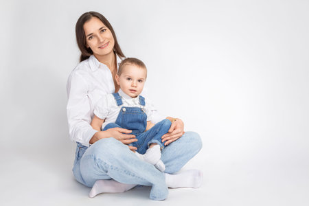 Cheerful Happy Couple Woman And Child Boy In Casual Clothing Having Mommy Little Kid Son in Jeans Jacket Hugging Cuddle While Posing on White. Horizontal Image Compositionの写真素材