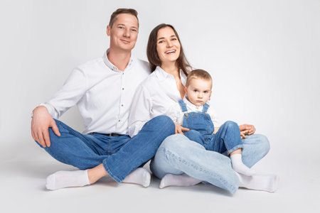 Adorable Smiling Happy Parents Mom and Dad With Little Son Child Kid Boy On Casual Jeans Clothing  Hugging Gladly Together Over White To Convey Traditional Family Relationships Ideas. Horizontal Imageの写真素材
