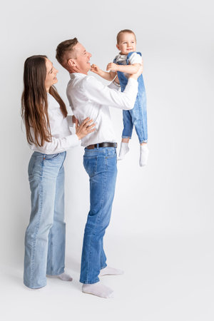 Smiling Happy Caucasian Parents Mom and Dad With Little Son Child Kid Boy Wearing Casual Jeans Clothing Gladly Together Hugging as Traditional Family Relationships Concepts.Vertical Shotの写真素材