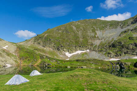 Mountain landscape with camping tents near the lake.の写真素材
