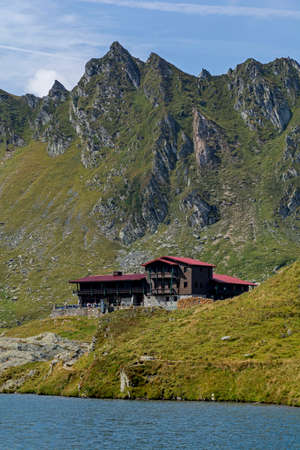 Wooden chalet under the summit on the shores of blue mountain lake.の写真素材