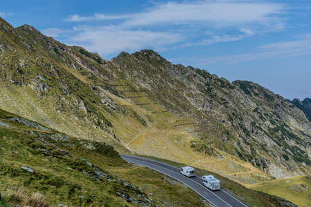 Mountain landscape with road and moving caravan travel trailers. Transfagarasan mountain road view.の写真素材
