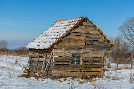 Landscape of old abandoned farm house covered with snow in a frosty winter. Old broken house in winter season.の写真素材