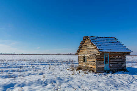 Landscape of old abandoned farm house covered with snow in a frosty winter. Old broken house in winter season.の写真素材