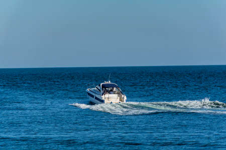 White cabin cruiser over blue water. A luxury private motor yacht under way on Black Sea sea with bow waveの写真素材