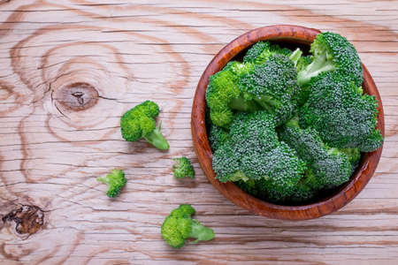 Fresh organic broccoli in wood bowl over rustic wooden background
