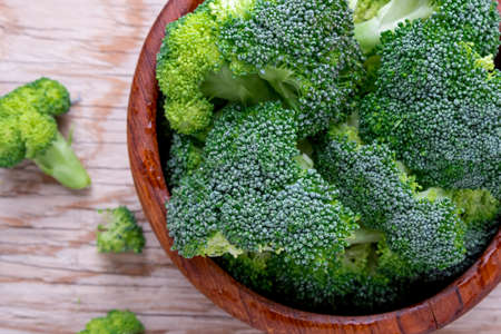 closeup Fresh organic broccoli in wood bowl over rustic wooden backgroundの写真素材
