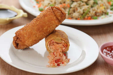 two egg rolls on the wood table with white dishの写真素材