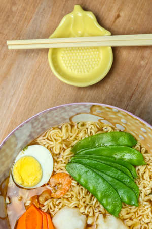 Chinese noodles soup with vegetables and egg on a wood tableの写真素材