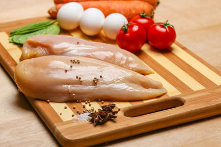 Fresh raw chicken fillet and vegetables prepared for cookingの写真素材