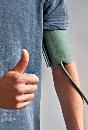  	Blood Pressure Measuring of a young man with his thumb upの写真素材