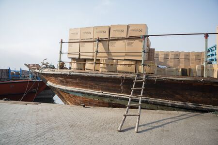 Dubai Creek dhow boat moored about o unload different goods on the pier, United Arab Emirates