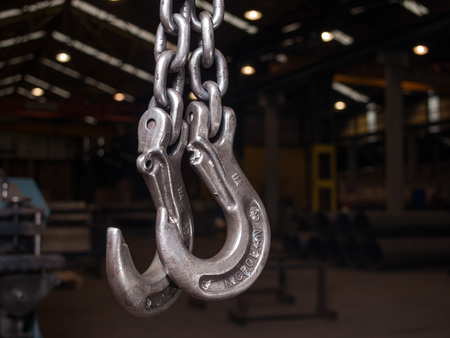 Heavy iron hooks hanging in a factoryの写真素材
