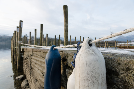 The Lake District, Keswick, England, 01/17/2016, Winter lakeside view with jetty mooring posts and snowy mountains in the backgroundのeditorial素材