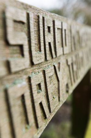 Hand carved chiseled letters on an old wooden bench covered in mossの写真素材