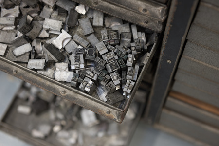 Vintage lead letterpress printing blocks against a weathered metal drawer background with bokeh.の写真素材