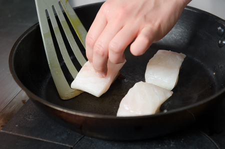Pan fried golden fish fillet cubes, frying in real butter, in a non stick rustic pan.の写真素材