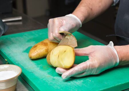 Peeling potatoes on a green cutting board.の写真素材
