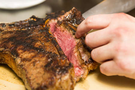 A knife slicing through a delicious grilledT Bone steakのeditorial素材