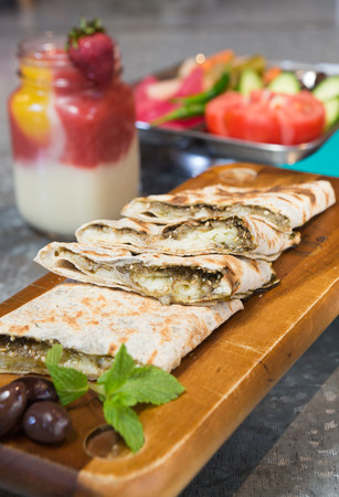 Lebanese manakeesh manouche with zaatar, served on a rustic wooden board with mint leaves, olives...