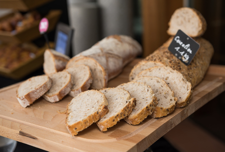 Fresh, warm organic wholemeal bread, with seeds, sliced on a rustic wooden cutting boardの写真素材
