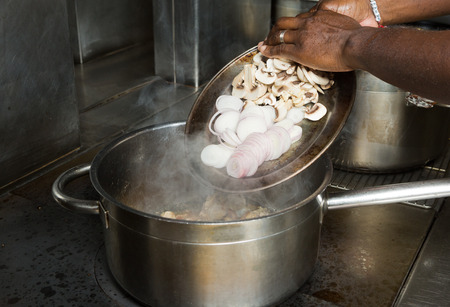 Raw organic sliced mushroom and onion being placed into a pan of hot oil.の写真素材