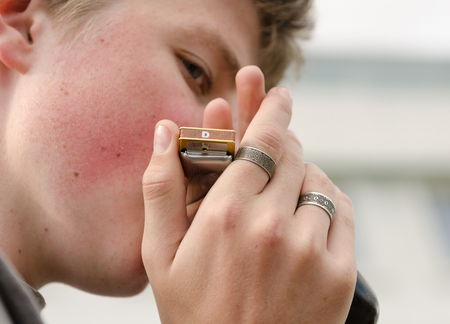 London, England, 04/18/2016, A young boy busking on the streets of london, playing the harmonicaのeditorial素材