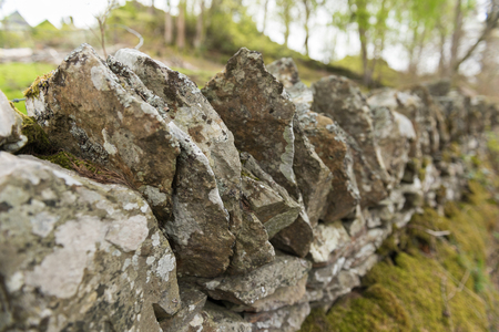 Old dry stone wall in the english countryside vanishing into the distance, with shallow depth of fieldの写真素材