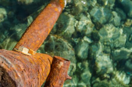 A vibrant orange rusty old jetty support, with sea and rocks belowの写真素材