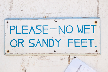 No wet or sandy feet sign. hand painted rustic sea weathered sign on a textured wall.の写真素材