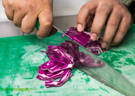Organic red cabbage being sliced and diced on a green vegetable cutting board.の写真素材
